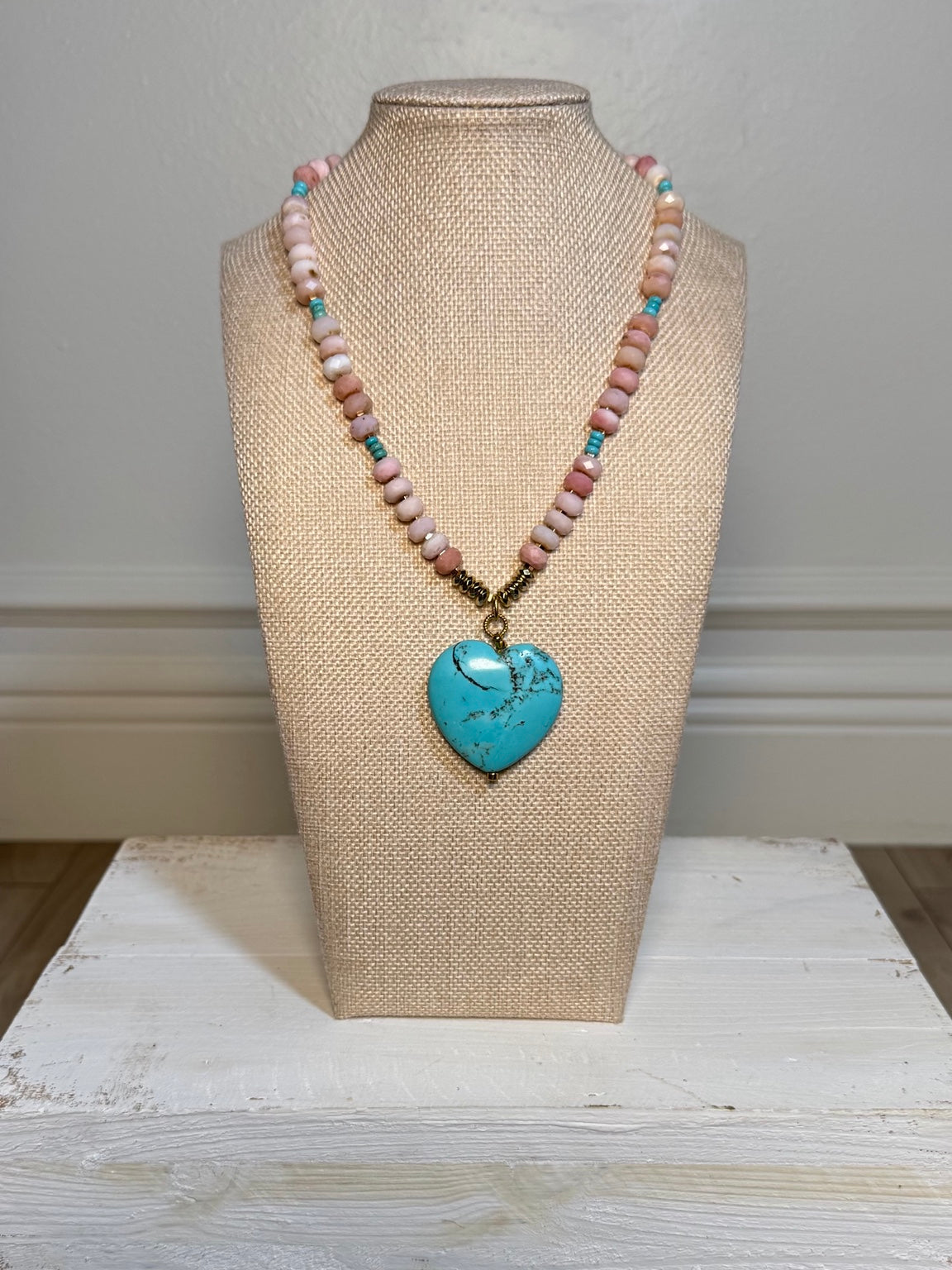 Pink opal and turquoise heart necklace displayed on a bust