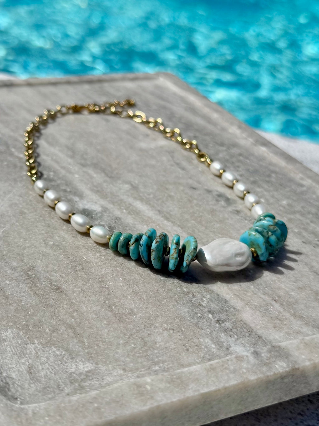 Close poolside view of dyed howlite discs, freshwater pearls, and baroque pearl necklace