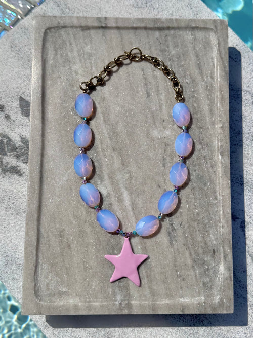 The Bonnie pink opal star necklace photographed poolside