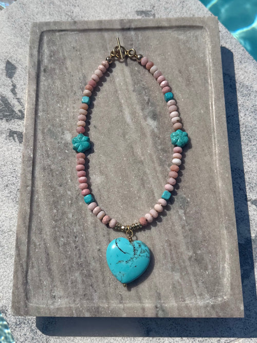 The Colt pink opal and turquoise flower heart necklace photographed poolside