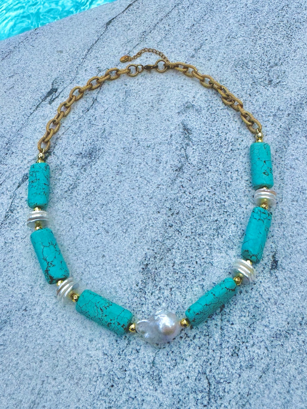 Angled poolside view of turquoise barrel and baroque pearl necklace