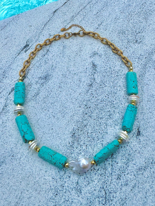Angled poolside view of turquoise barrel and baroque pearl necklace