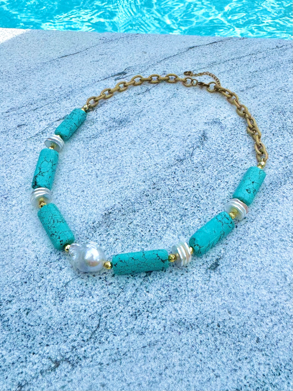 Close view of turquoise barrels, shell discs, hematite, and baroque pearl necklace