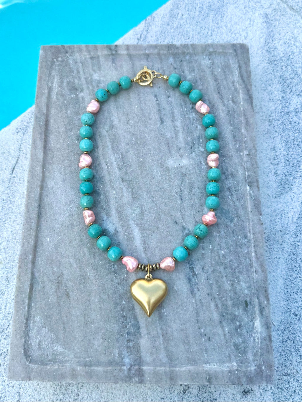 Full view of turquoise and pink pearl necklace with gold heart charm