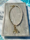 White shell disc and gold charm necklace photographed poolside