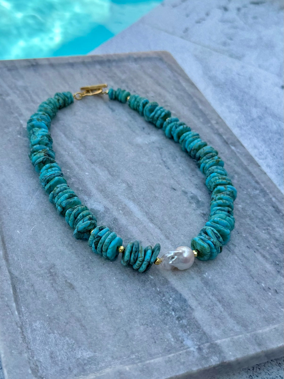 Close poolside view of The Mackenzie dyed howlite and baroque pearl necklace