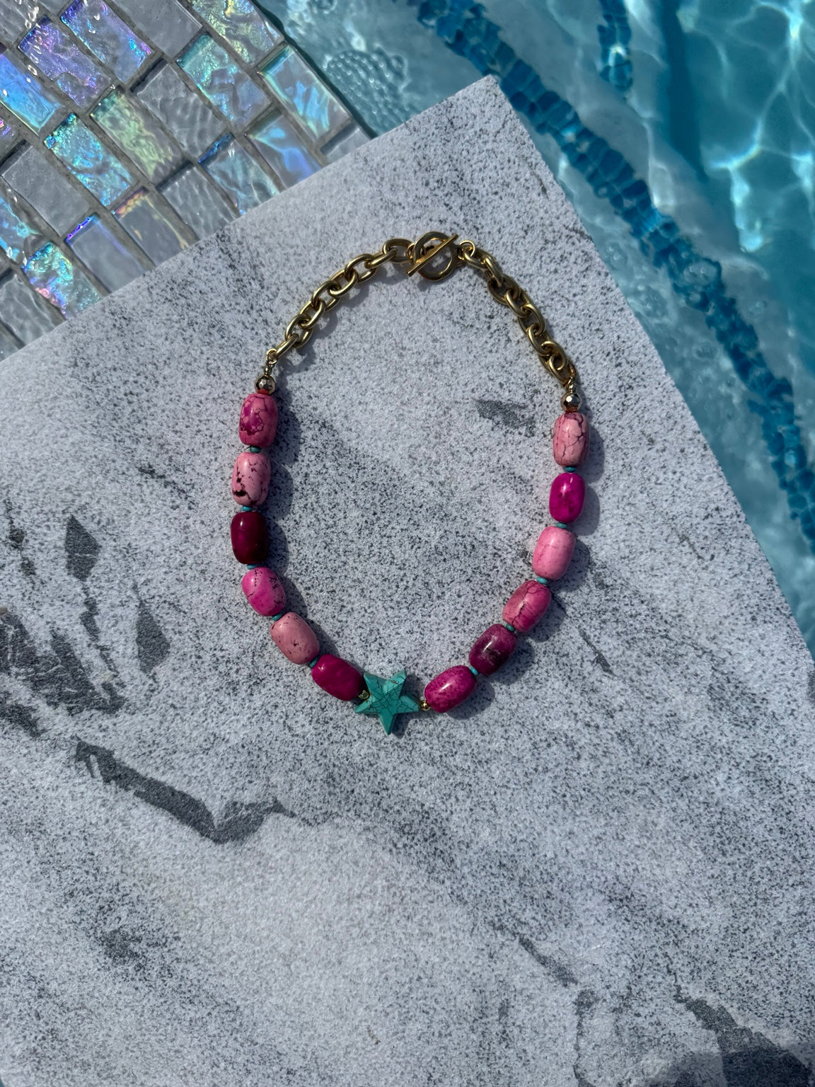 Angled poolside view of pink turquoise barrel necklace with turquoise star
